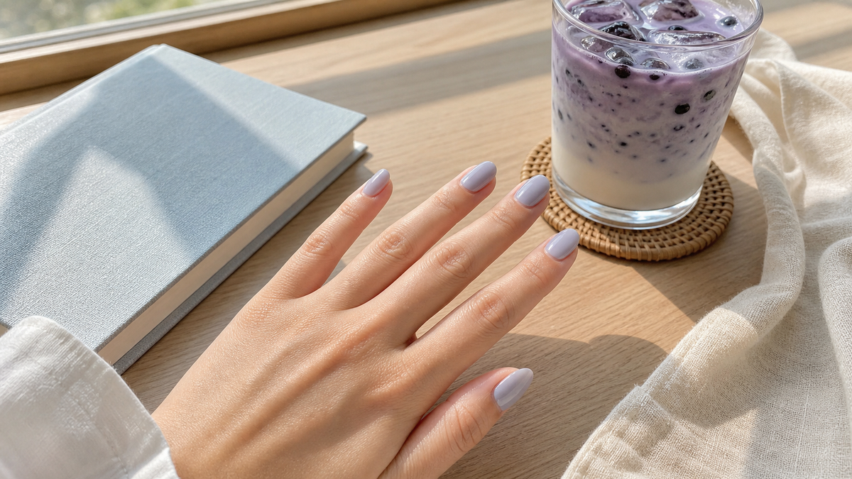 Blueberry milk nails on a relaxed left hand beside an iced blueberry latte in late-summer window light